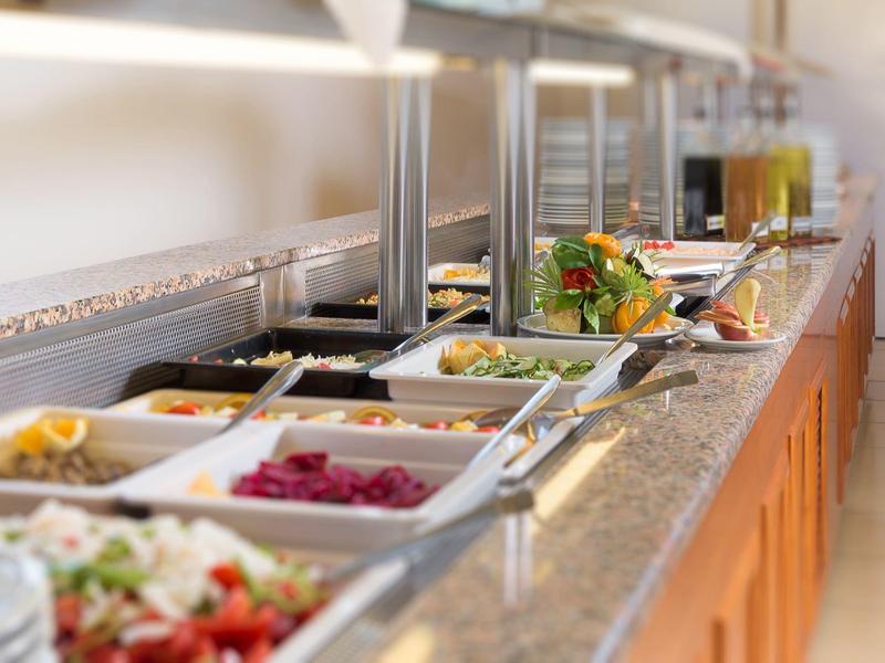 Buffet with various salads and dishes on a long counter in a bright dining area.