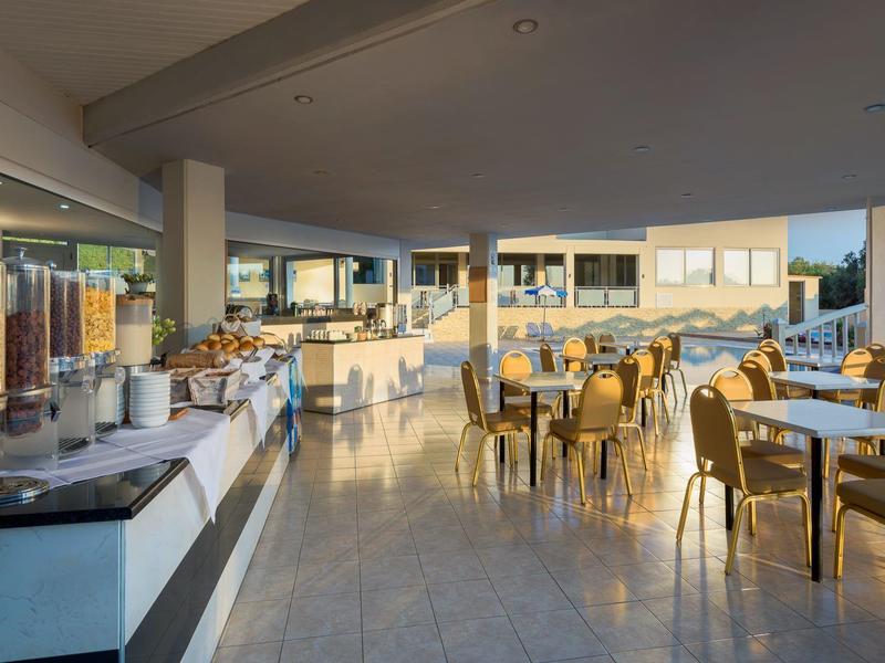 Spacious hotel breakfast area with cereal dispensers and tables bathed in natural light.