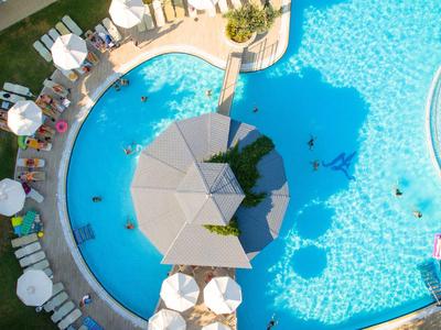 Luftaufnahme eines runden Pools mit Sonnenschirmen und Liegestühlen auf einer Hotelterrasse.