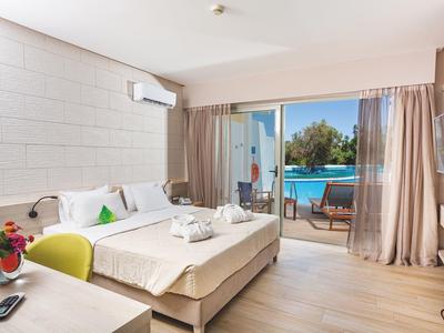 Jasny pokój hotelowy z podwójnym łóżkiem, biurkiem i przesuwanymi drzwiami na patio z widokiem na basen.