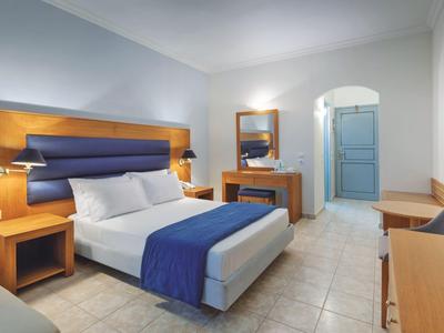 Modern eingerichtetes Hotelzimmer mit Doppelbett, blauem Bettläufer und Holzmöbeln.