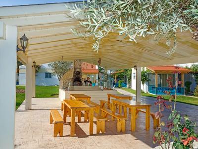 Überdachter Außenbereich mit Holztischen und -bänken in einer Hotelanlage.