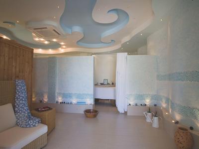 Nowoczesny pokój spa z zakrzywionymi ścianami, miękkim oświetleniem i spokojnym wzorem sufitu.