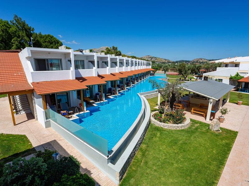 Nowoczesny hotel z pokojami przy basenie, dużym basenem i zielonym trawnikiem przy słonecznej pogodzie.