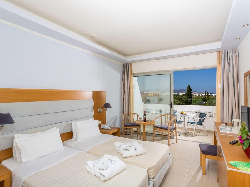 Pokój hotelowy z dwoma łóżkami, balkonem z widokiem na miasto i nowoczesnymi drewnianymi meblami.