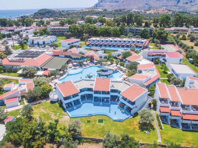 Widok z lotu ptaka na duży kurort z wieloma budynkami, basenami i otaczającą zielenią.