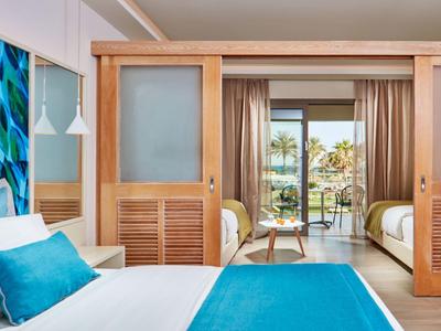 Helles Schlafzimmer mit Holzmöbeln, blauen Akzenten und Blick auf Terrasse mit Garten.