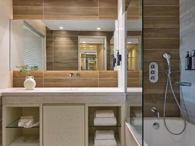 Baño moderno con espejo grande, lavabo, toallas y zona de ducha.