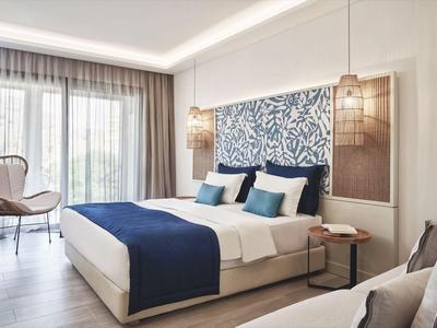 Modernes Hotelzimmer mit großem Bett, Blautönen und zwei Hängelampen neben dem Kopfteil.