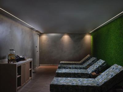 Sala de relax moderna con tumbonas, iluminación LED y pared verde en el área de spa.