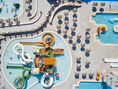 Widok z góry na basen hotelowy z zjeżdżalniami i leżakami pod parasolami.