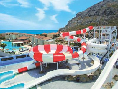 Blick auf einen Wasserpark mit Wasserrutschen und Pool vor einer Berglandschaft.