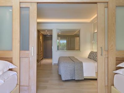 Habitación de hotel modernamente amueblada con dos camas y puertas de madera.