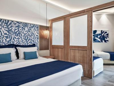 Habitación de hotel moderna con cama doble, separador de habitación de madera y decoración azul en la pared.