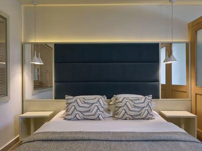 Habitación de hotel moderna con cama grande, dos almohadas, mesas de noche y iluminación elegante.