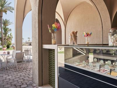 Vitrina de helados en un café mediterráneo abierto con arcos y asientos al aire libre.