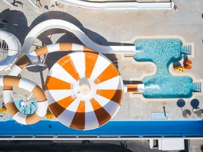 Vista aérea de un parque acuático con toboganes y una gran estructura acuática naranja y blanca.