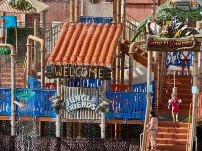 Bunter Wasserpark mit Rutsche, Treppe, Plantschbecken und Willkommensschild "Welcome to Jungle Friends".