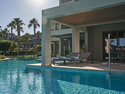 Moderner Poolbereich mit Sonnenliegen und Palmen in einem Hotelresort