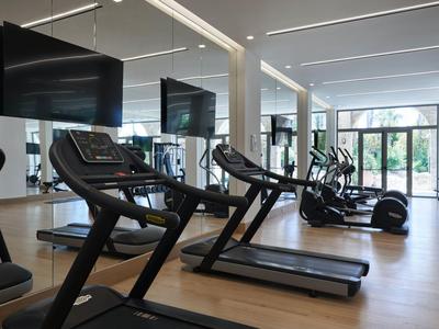 Gimnasio moderno con cintas de correr y grandes espejos en un hotel luminoso