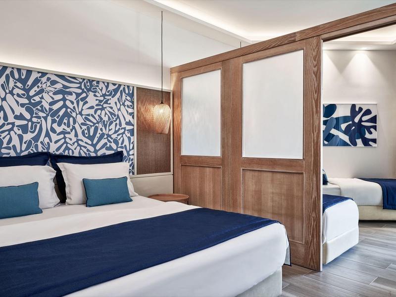 Modernes Schlafzimmer mit blauen Mustern, zwei Betten und hölzernen Raumteilern mit weißen Feldern.