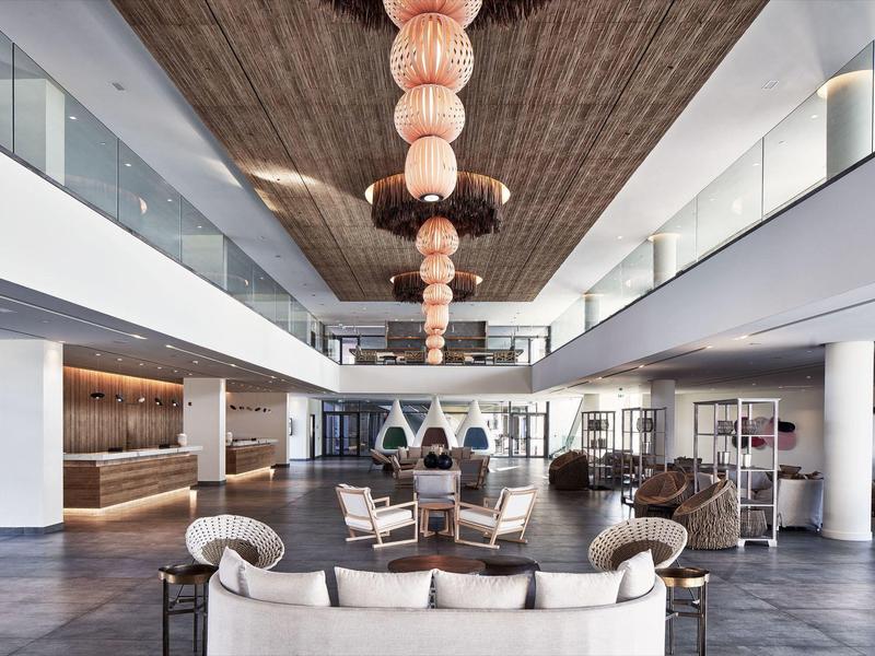 Moderner, geräumiger Lobbybereich mit Leder- und Stoffmöbeln, Holzdecke und großen Glasfenstern.