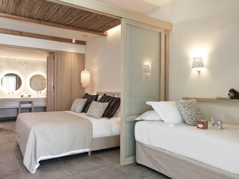 Modern eingerichtetes Schlafzimmer mit Doppelbett, Tagesbett, Holzdecke und indirekter Beleuchtung.