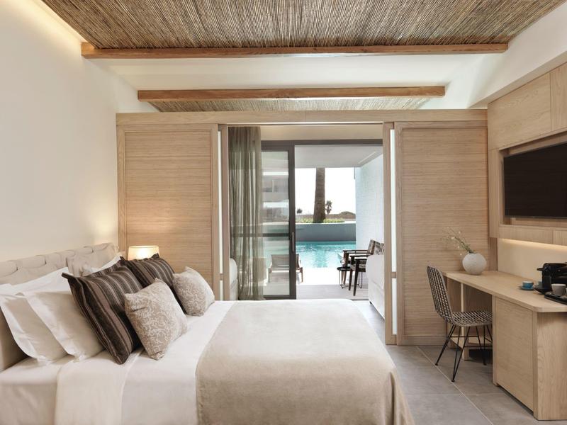 Modernes Schlafzimmer mit großem Bett, Holzmöbeln, Fernseher und Blick auf einen Pool durch Glasschiebetüren.