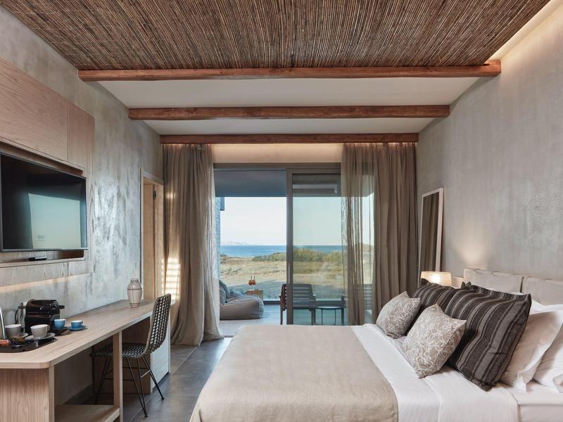 Modernes Hotelzimmer mit Bett, Schreibtisch, Fernseher und Balkon mit Meerblick.