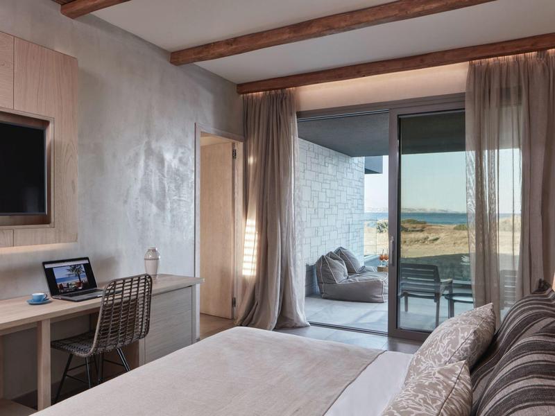 Modernes Schlafzimmer mit großem Bett, Schreibtisch, TV und Zugang zu Balkon mit Landschaftsblick.