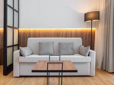 Modern eingerichtetes Wohnzimmer mit grauer Couch, Holztisch und warmem Licht.