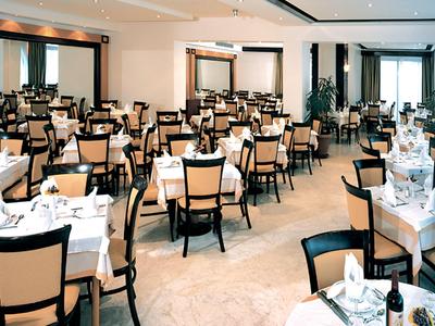 Großer heller Speisesaal mit vielen gedeckten Tischen und braunen Holzstühlen.