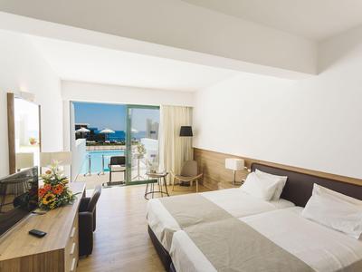 Modernes Hotelzimmer mit Doppelbett, Balkon und Meerblick.