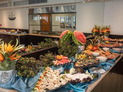Buffet mit verschiedenen Meeresfrüchten, Obst, Blumenarrangements und blauem Tischtuch.