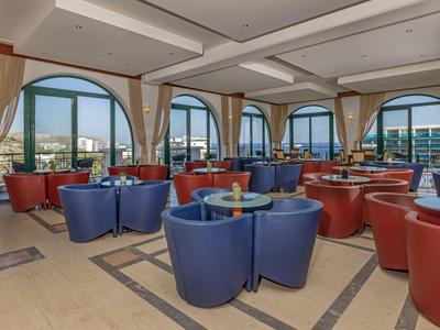 Modernes Hotelrestaurant mit bunten Sesseln und großen Fenstern mit Aussicht auf die Stadt.