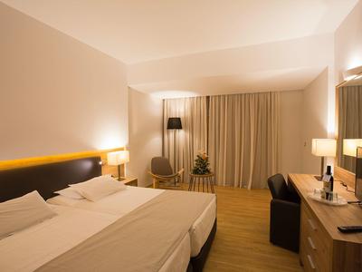 Modernes Hotelzimmer mit zwei Einzelbetten, Schreibtisch, Stuhl und Vorhängen.