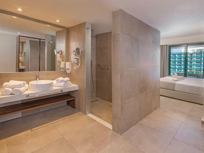 Modernes Badezimmer mit begehbarer Dusche und Blick ins Schlafzimmer in einem Hotelzimmer.