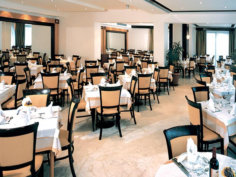 Großer heller Speisesaal mit vielen gedeckten Tischen und braunen Holzstühlen.