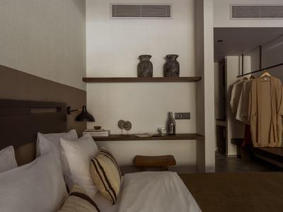 Gemütliches Schlafzimmer mit braunen und weißen Kissen, Holzregalen und beigem Bademantel.
