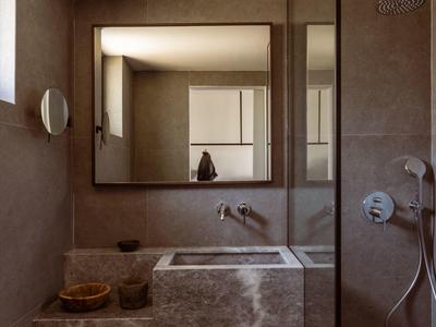 Modernes Badezimmer mit braunem Marmorwaschbecken, großem Spiegel und Duschbereich in schlichtem Design.