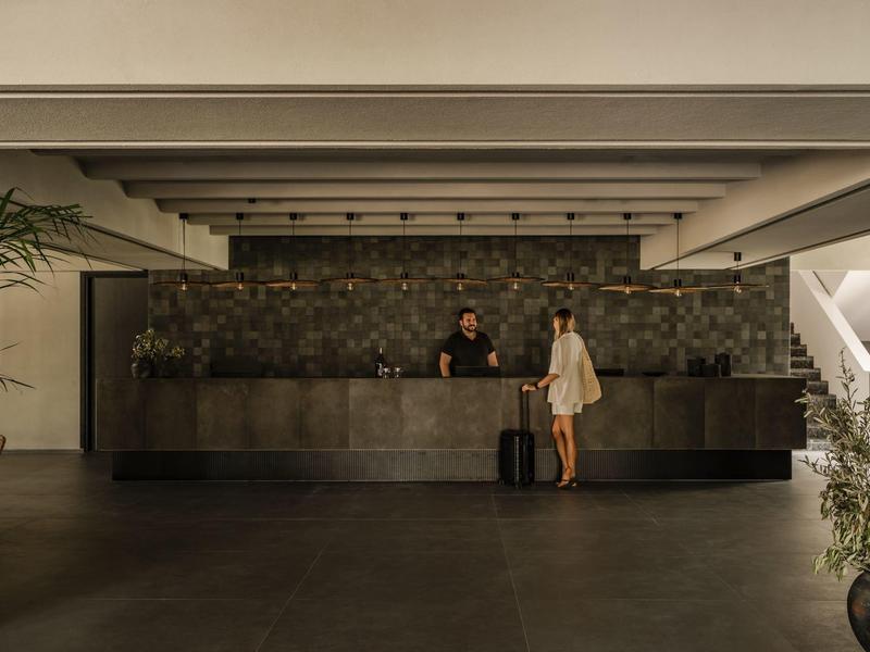 Hall dell'hotel con reception e un viaggiatore con valigia.