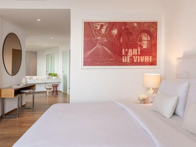 Camera d'hotel moderna con letto grande, arte murale rossa e scrivania con specchio rotondo.