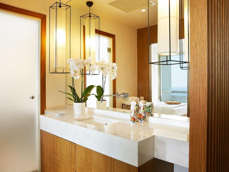 Bagno moderno con mobili in legno, doppi lavandini e orchidea in fiore.