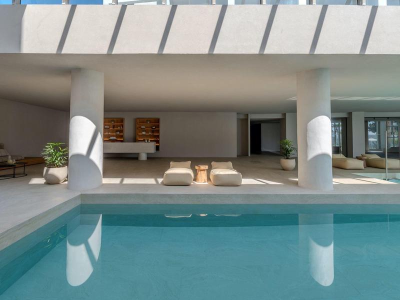 Area esterna moderna con piscina, sedie a sdraio e spazio abitativo aperto sotto un tetto piano.