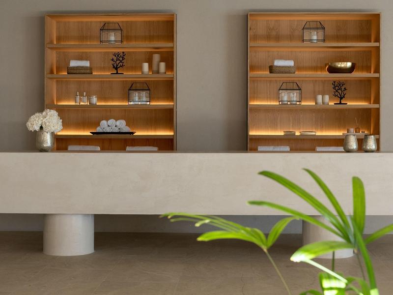 Interno moderno di un hotel con scaffali in legno illuminati e bancone grigio in primo piano