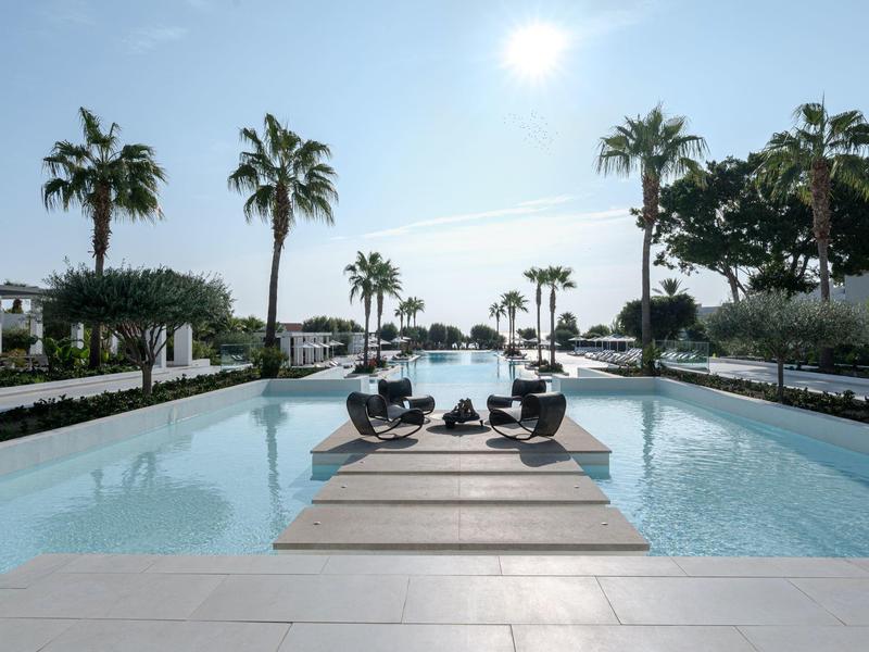 Grande piscina all'aperto con lettini e palme in una giornata di sole
