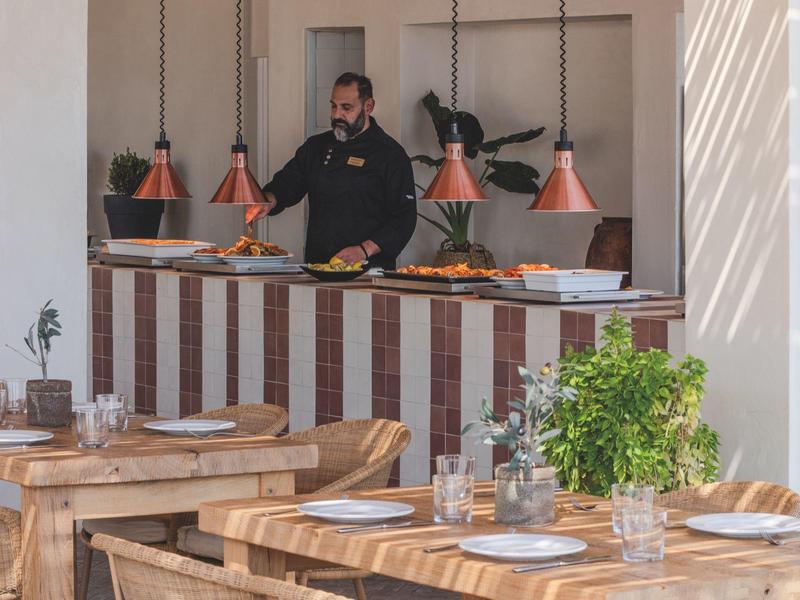 Area bar con lampade a sospensione in rame e tavoli apparecchiati con posate e bicchieri