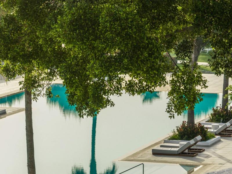 Area piscina con lettini e alberi che offrono ombra