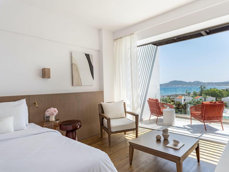 Camera d'hotel moderna con balcone, vista mare e arredi confortevoli.