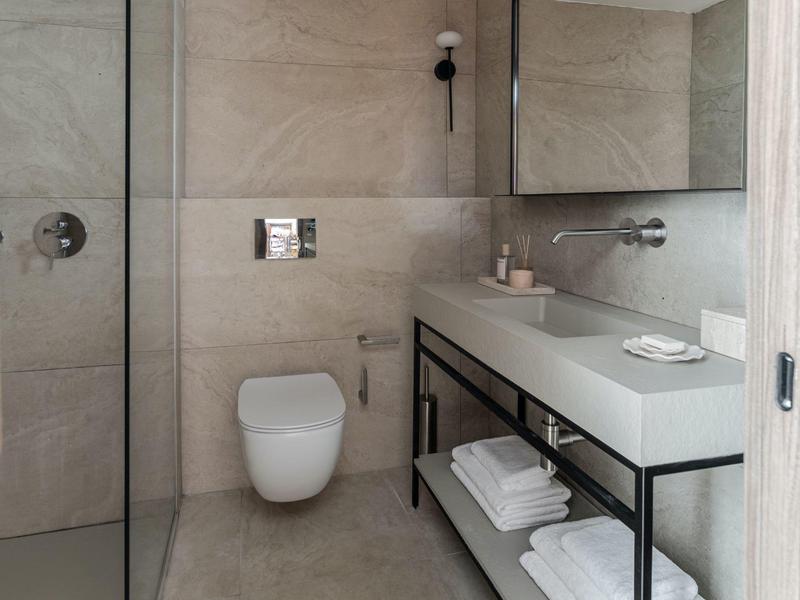Bagno moderno con WC bianco, grande specchio e lavabo su telaio nero.